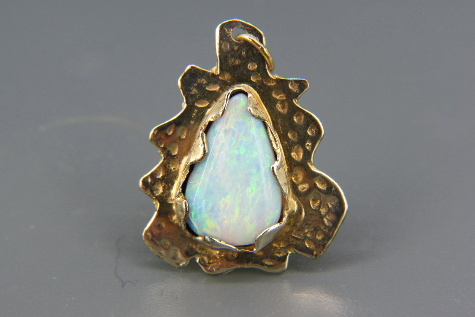 Opal 14K Gold Pendant,: pear shaped fiery gem with blue, green, red and orange colors, 4.56 carat, 14K yellow gold, small crack in a corner, with appraisal of $1,950.00, 1 1/4" long pendant.
