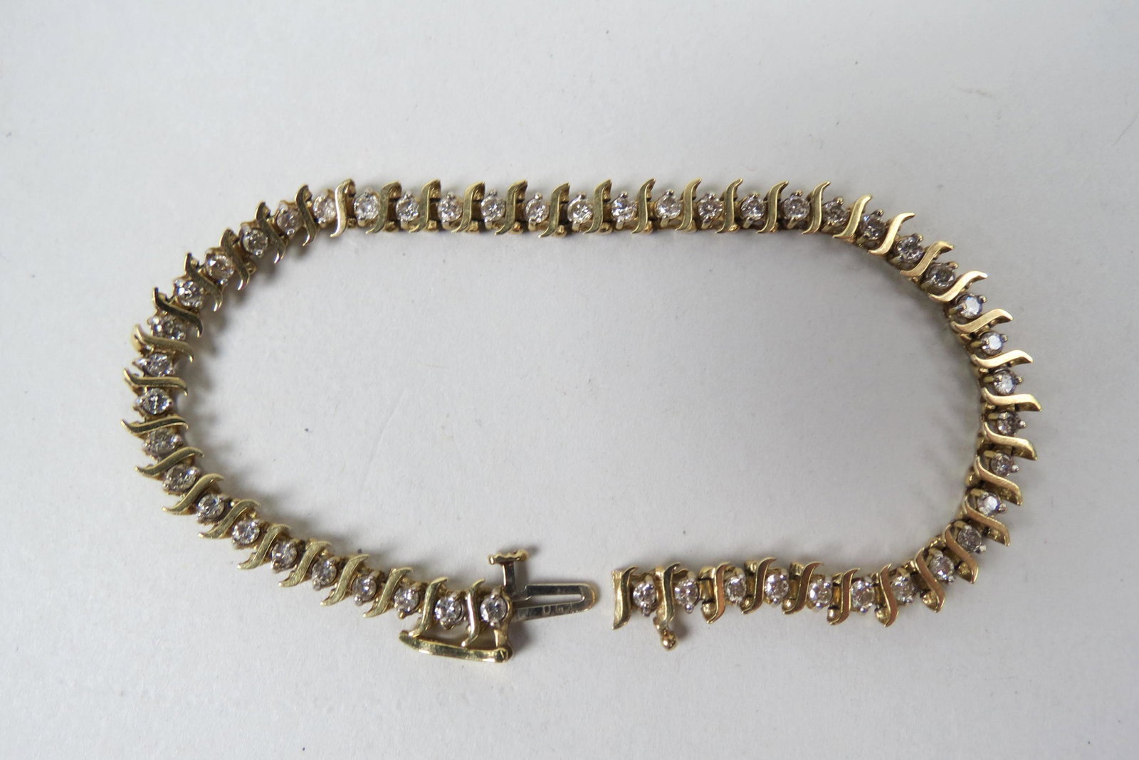 Diamond Tennis Bracelet,: 52 round diamonds totaling 1 carat in 14K yellow gold, with appraisal of $2,550.00, 7 1/8" ong.