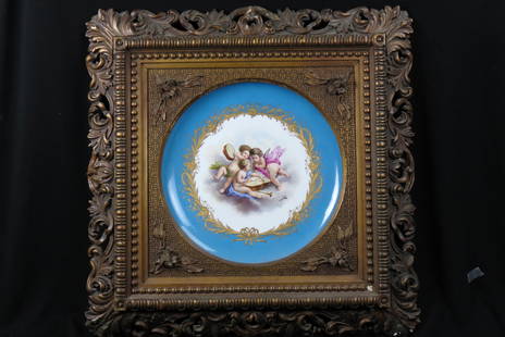 Sevres Porcelain Charger with Cherubs, framed,: scene of three cherubs with musical instruments, blue and gold trim, 16" diameter in elaborate gold frame, overall 28" X 28", 19th century.