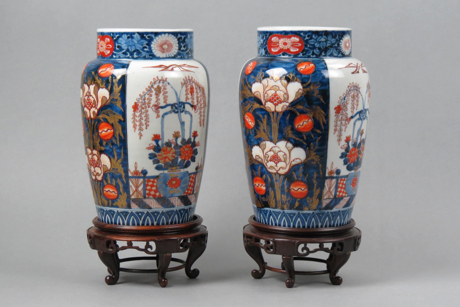 Pair of Japanese Imari Porcelain Vases,: weeping tree and floral designs on alternating panels, 10" tall plus carved wooden stands, circa 1890, one has spider crack in base other excellent.