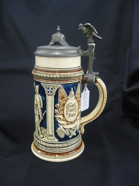 German Pottery Military Stein, figural helmet: pewter top dated 1899, bas-relief scene with soldiers, 9" tall