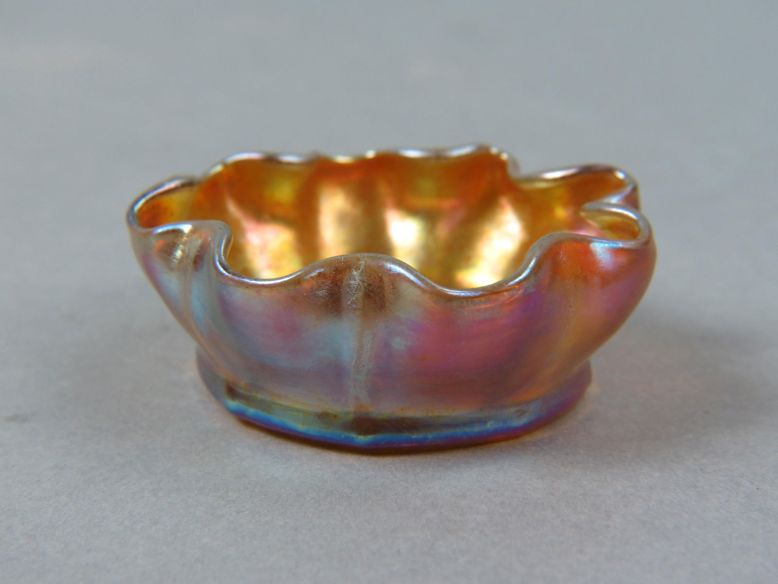 Tiffany Favrile Art Glass Salt Cellar,: golden iridescent with rainbow hues on exterior, floraform shape, 2 1/2" diamter, 1" tall, signed L.C.T., excellent.