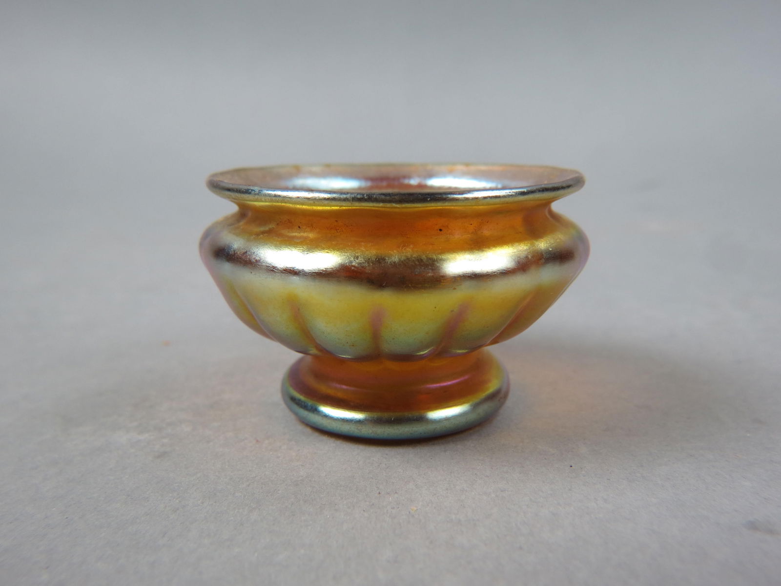 Tiffany Favrile Art Glass Salt Cellar,: golden iridescent with ribbed design, miniature puchbowl shape with low pedestal base, 1 1/2" tall, 2 3/8" diameter, signed L.C.T.