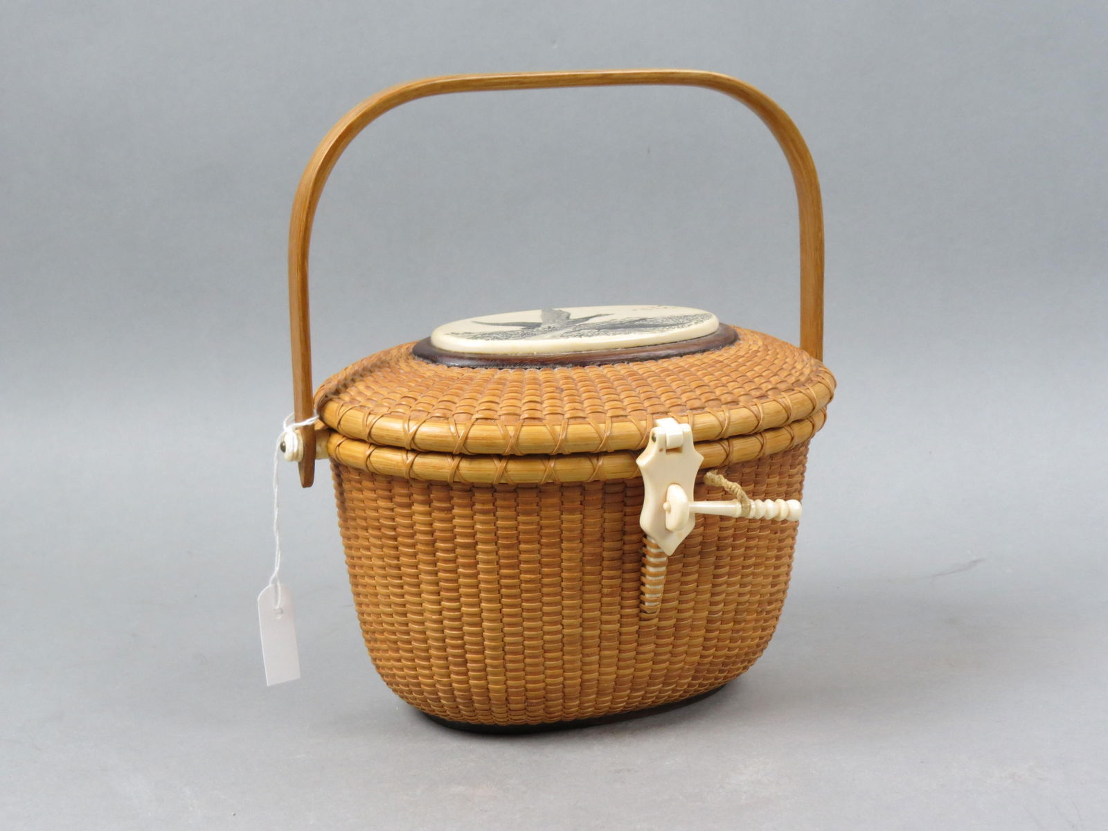 Original Nantucket Basket by Kathy E. Loring,: with scrimshaw plaque on top with flying geese done by her husband, Robert Loring, 6" X 8", 5 1/2" tall plus swing handle, signed and dated 1987, name tag inside underneath the lid for whom it was cus