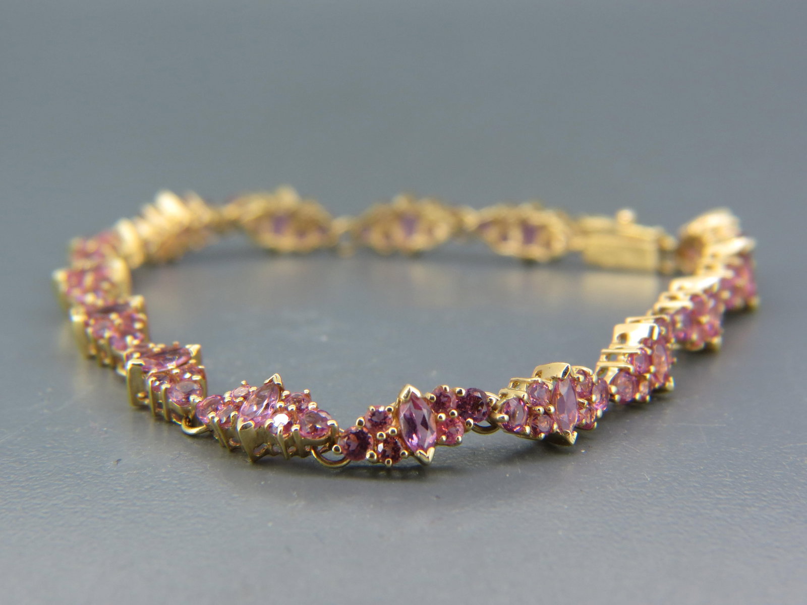 Pink Sapphire 14K Gold Bracelet,: with 90 round and 15 marquise cut pink gems totaling 10.50 carats in 14K yellow gold, with appraisal of $2,350.00, 7" long.