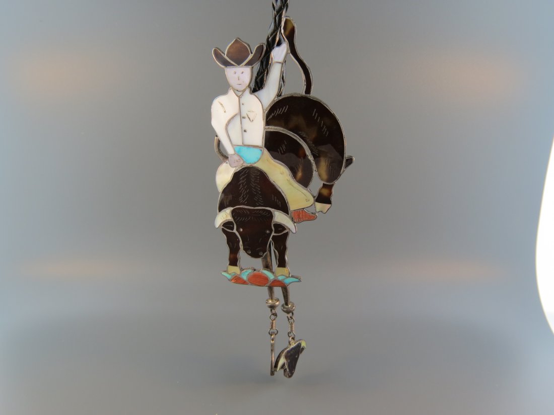 Indian Figural Bolo Tie,: rodeo rider on bull, inlaid tortoise shell, abalone, coral, turquoise & more in sterling silver, 4 1/4" x 2 1/4".