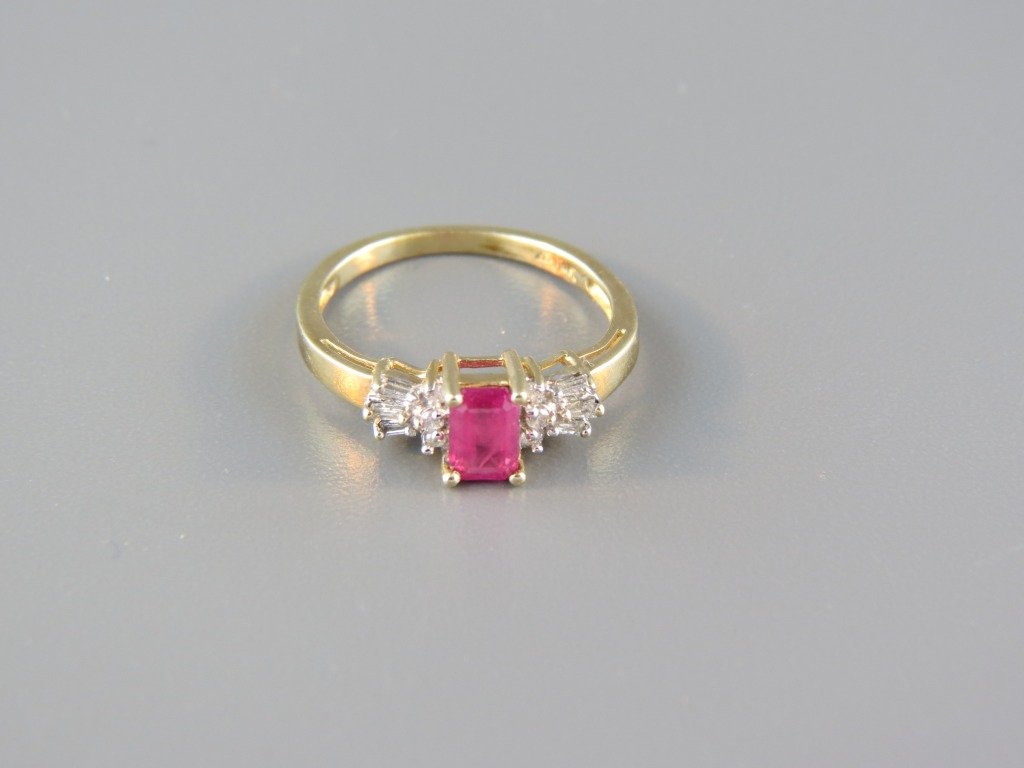 Ruby & Diamond Ring,: .75 carat emerald cut gem with a trio of round & baguette diamonds on each side in 10k yellow gold.