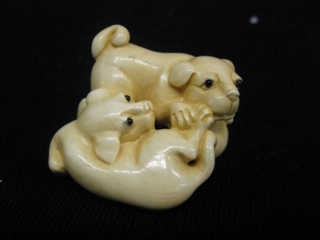 Carved Ivory Netsuke of Two Foo Dog Pups: at play, signed, 1" x 1 3/4".