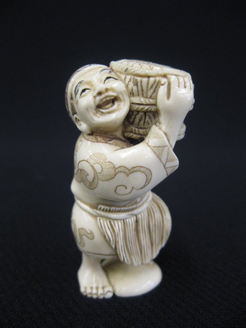 Carved Ivory Netsuke of a Man,: carrying a large basket of fish, signed, 2".