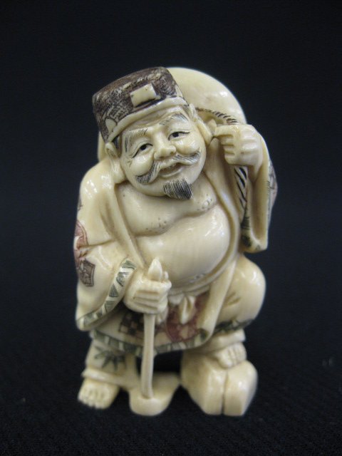 Carved Ivory Netsuke of The god of Harvest,: wearing a large hat and holding a hoe, signed, 2".