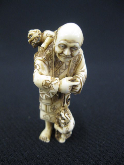 Carved Ivory Netsuke,: man with two oni or mischief makers, signed, 2".