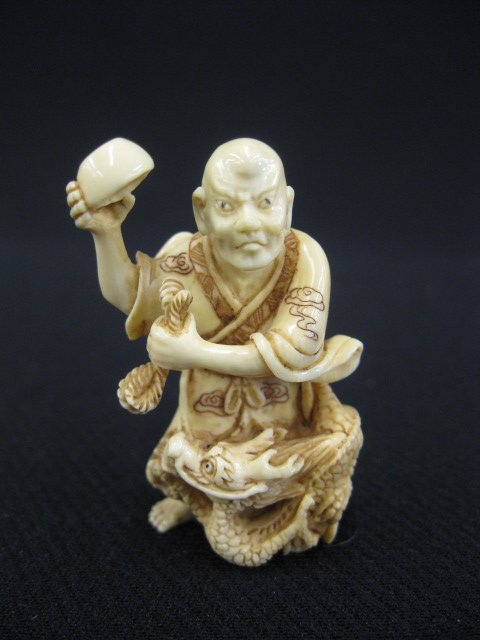 Carved Ivory Netsuke of a Man: with dragon and empty bowl, fancy polychrome, 1 7/8", signed.