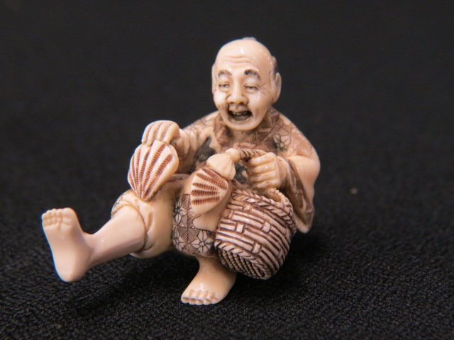 Carved Ivory Netsuke of a Seated Man,: holding scallops and a basket, 2" long, excellent.