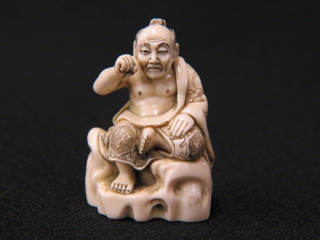 Carved Ivory Netsuke of a Seated Man,: with raised arm, 2", signed, excellent.