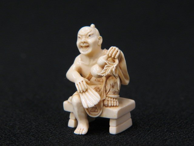Carved Ivory Netsuke of a Man Seated on a Bench,: holding a fan and a gourd, 1 5/8", signed.