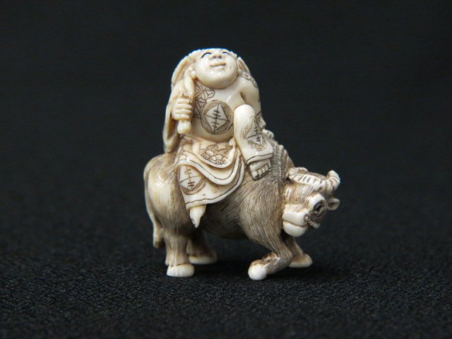 Carved Ivory Netsuke of a Man: riding a water buffalo, 1 3/4" tall, signed, excellent.