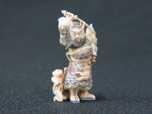 Carved Ivory Netsuke of Shokie: (a demon queller) holding a sword with two Onis (demon) nearby, 2 1/2", fancy polychrome, signed, excellent.