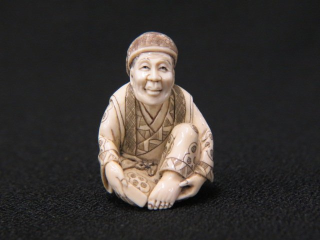 Carved Ivory Netsuke of a Seated Man,: polishing his toenails, 1 1/2" tall, signed, excellent.