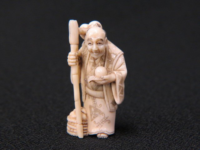 Carved Ivory Netsuke of a Farmer,: holding a staff, basket with harvest at feet, 1 7/8", signed, excellent.