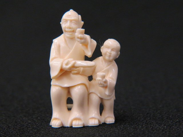 Carved Ivory Netsuke,: man seated in his chair, holding a rice bowl, child at his side, 1 5/8" tall, signed, excellent.