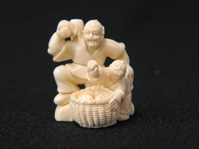 Carved Ivory Netsuke of a Man,: holding a mallet, child with basket of fish, 1 1/2" tall, signed, excellent.