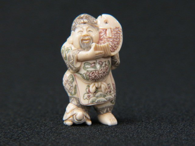 Carved Ivory Netsuke of Ebisu,: (god of fisherman) holding a fish while standing on a turtle, fancy polychrome, 1 3/4" tall, signed, excellent.