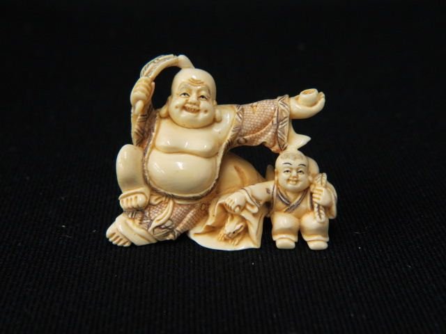 Carved Ivory Netsuke of Hotei,: god of happiness, holding a fan & saki cup, child & gourd at his side, 1 5/8", signed, excellent.