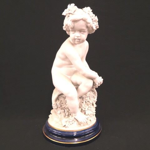 L. Badessi Porcelain Figurine of a Seated Child,: nude, seated, grapes all around, Parian finish, cobalt & gold base, 18 1/2", signed.