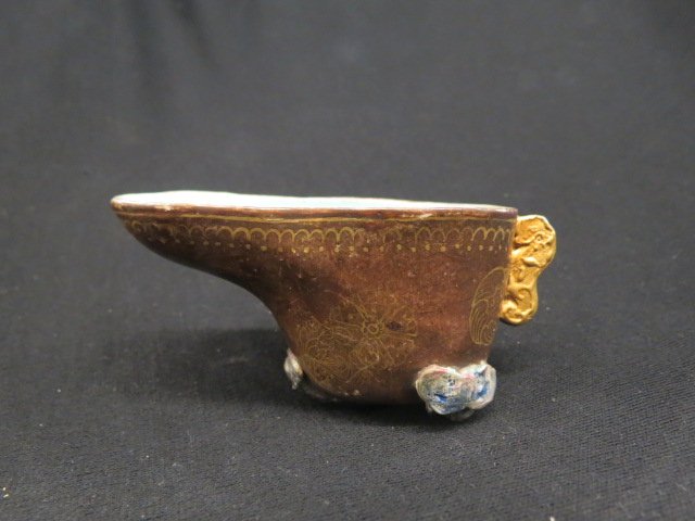 Chinese Porcelain Libation Cup, Qianlong Period: 1635-1695, tripedal cup with gild on russet glaze, Lingzhi form feetand handle, footed, gold floral medallions on brown field, blue interior, 2" x 4".