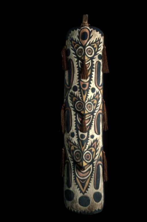 Papua New Guinea War Shield: #141 Colorful 71" high war shield with 3 faces on top of one another vertically with the same expression. Decorated in orange, black and white ochre.