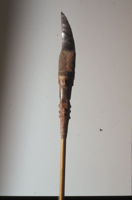 Papua New Guinea Obsidian Spear: #337 64.5" Long Spear with a face carved at the spear end with a dagger shaped like foolscap. There is some wood splitting.