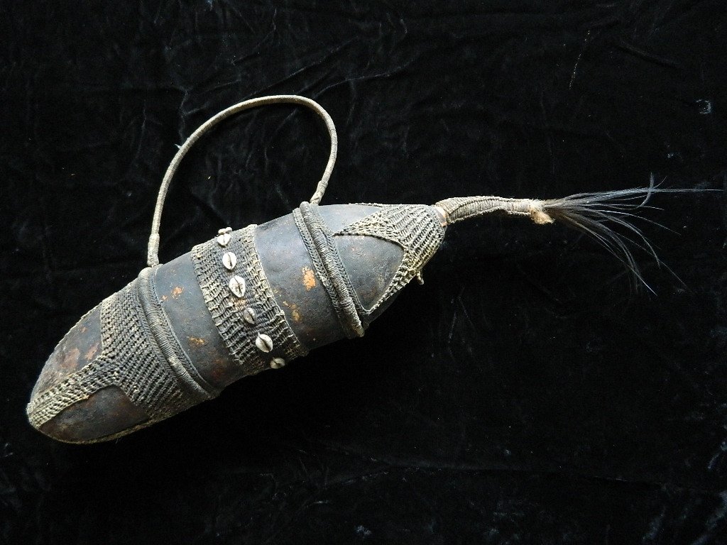 African Water Container Made From Gourd: We have a beautiful gourd from the Dani tribe decorated with twine, cowrie shells and cassowary feathers. It measures 29" long and 6" wide. For thousands of years indigenous cultures around the world 