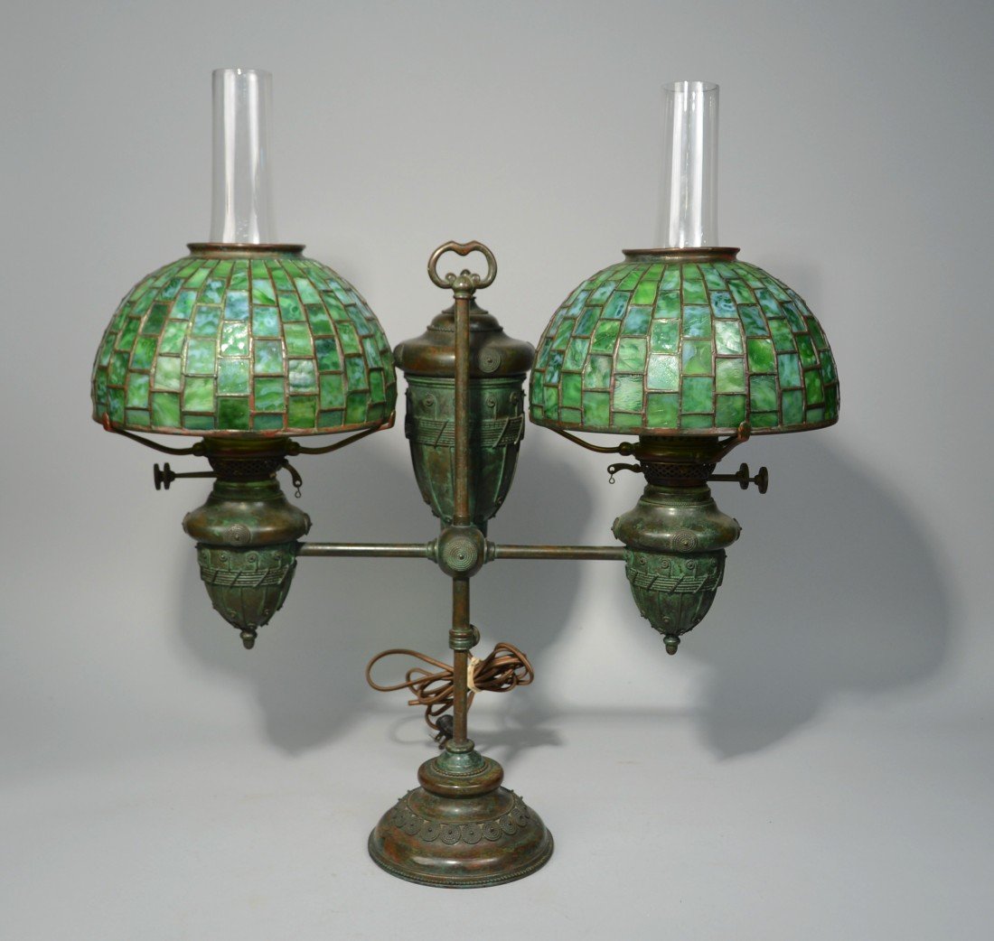 TIFFANY STUDIOS PATINATED BRONZE AND LEADED GLASS TWO L: TIFFANY STUDIOS PATINATED BRONZE AND LEADED GLASS TWO LIGHT STUDENTS LAMP; the base numbered 2124; each shade inscribed Tiffany Studios, New York; height of lamp: 22 inches; diameter of shade: 10 1/4 