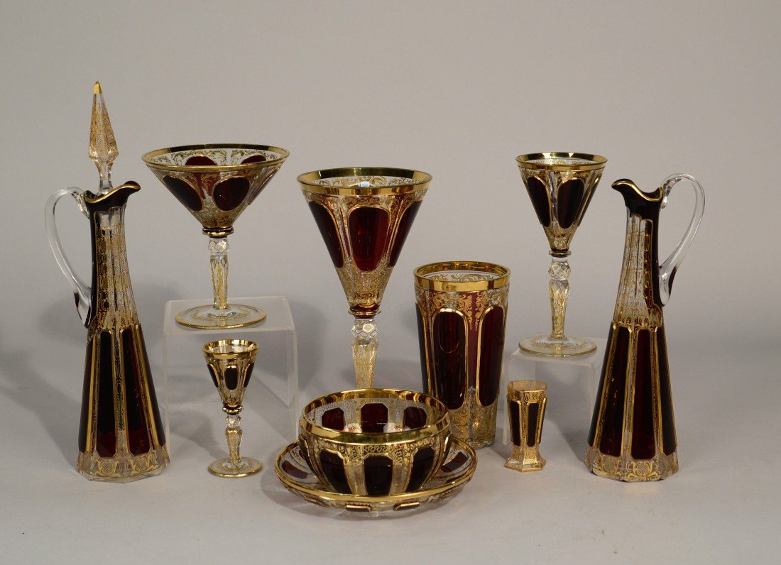LARGE COLLECTION OF CLARET RED AND GILT DECORATED GLASS: LARGE COLLECTION OF CLARET RED AND GILT DECORATED GLASS STEMWARE AND TABLEWARE, possibly Moser; including: 12 water glasses, 12 large wine glasses, 9 small wine glasses, 12 champagne glasses; 11 cordi
