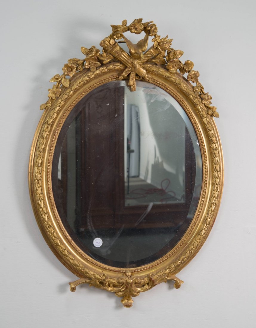 NAPOLEON III CARVED GILTWOOD OVAL MIRROR;: NAPOLEON III CARVED GILTWOOD OVAL MIRROR; with floral garland, bird and torch crest; height: 39 in., width: 26 in.
