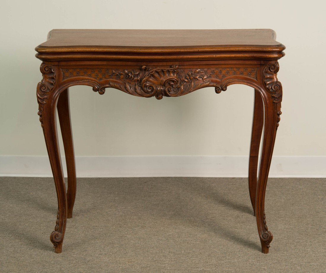 LOUIS XV STYLE CARVED WALNUT LIFT TOP GAMES TABLE;: LOUIS XV STYLE ELABORATELY CARVED WALNUT LIFT TOP GAMES TABLE; height: 29 in., width: 33 in., closed depth: 18 in.