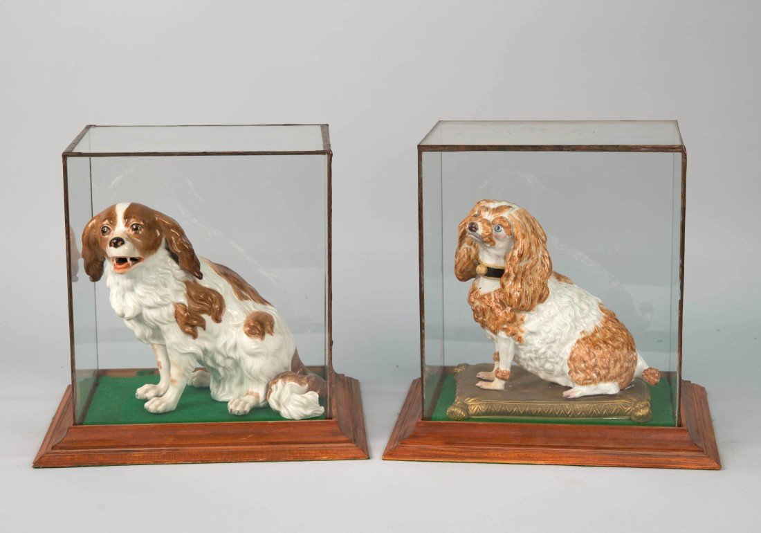 TWO CONTINENTAL PORCELAIN FIGURES OF SPANIELS;: TWO CONTINENTAL PORCELAIN FIGURES OF SPANIELS; one depicting a King Charles Spaniel, bearing a stamped Vienna beehive mark, height: 8 in.; the other a spaniel seated on a gilt bronze pillow base, bear