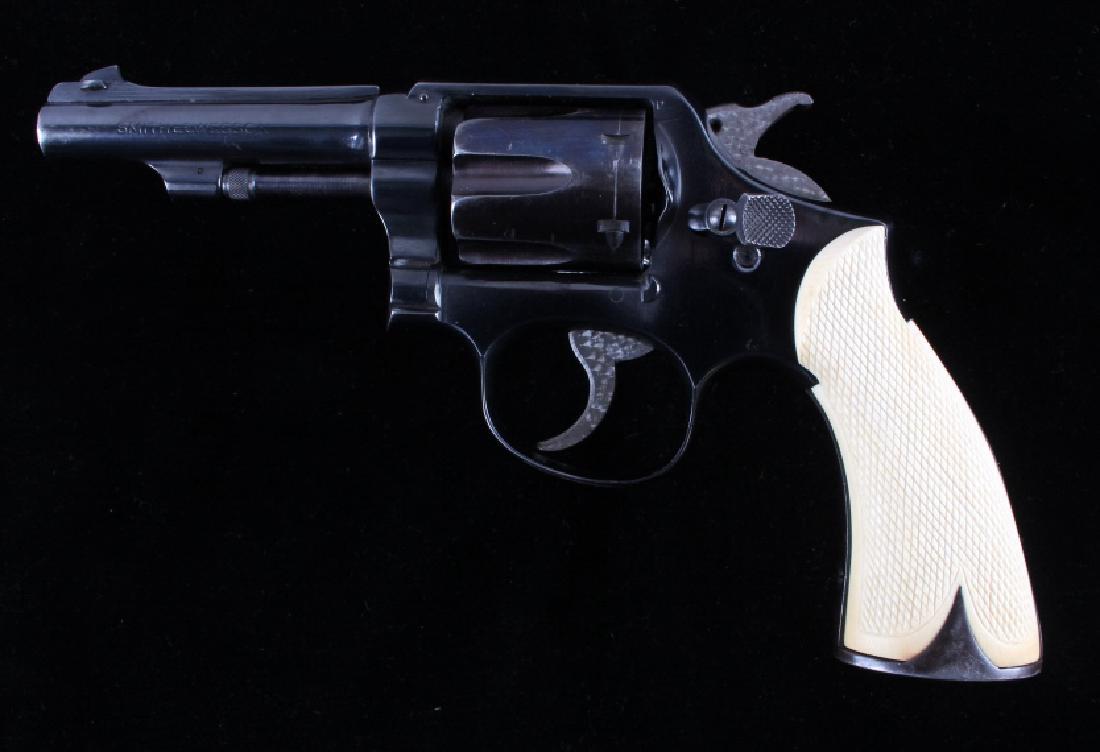 Smith & Wesson Custom .38 Spl. K Frame Revolver: This is a Smith & Wesson custom double action revolver chambered in .38 special. The revolver shows a blued frame, cylinder and 4" barrel with checkered ivory grips. The hammer and trigger have a jewe