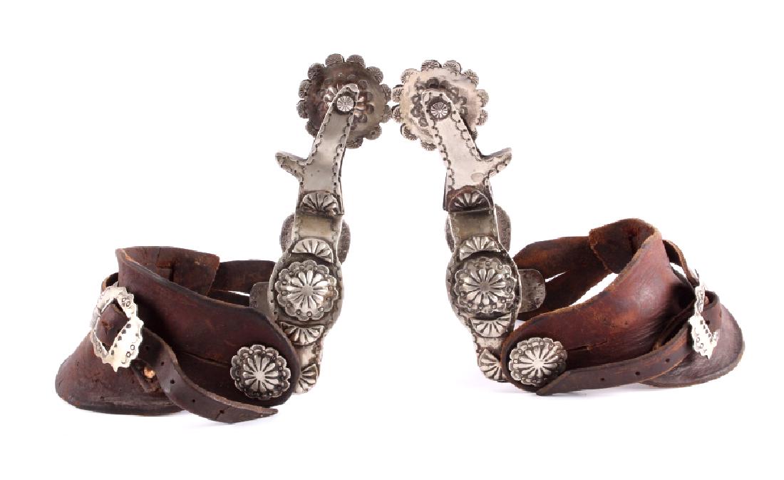 Early Fred Harvey Navajo Silver Spurs: This is a pair of Navajo Native American Indian silver spurs with leather straps made by Fred Harvey. The spurs show a wonderfully tooled design with concho accents throughout. Additionally, the outsi