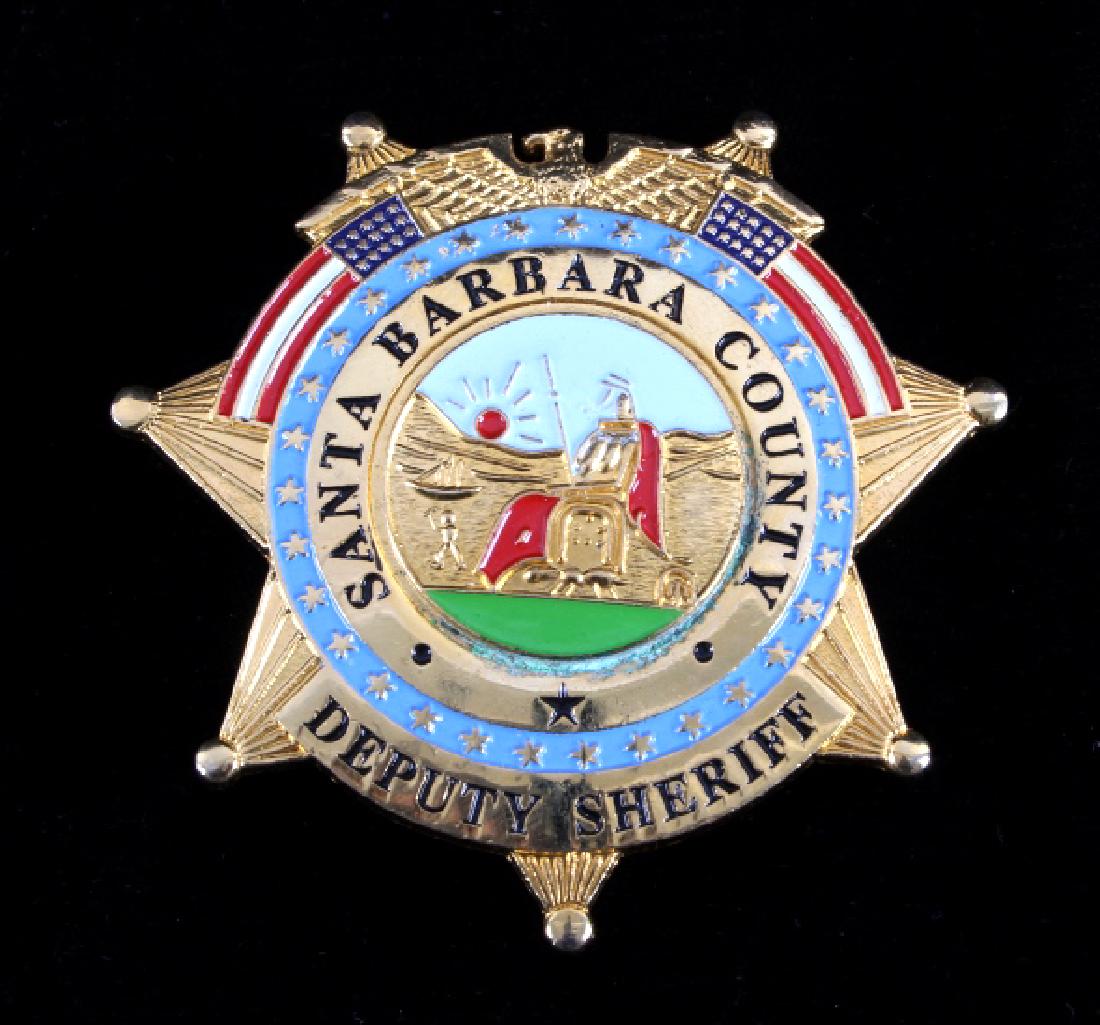 Santa Barbara County Deputy Sheriff Badge: This is a Santa Barbara County deputy sheriff badge. The badge shows a seven point star with an eagle at the top with two opposing flags. The seal of the State of California is in the center. The badg