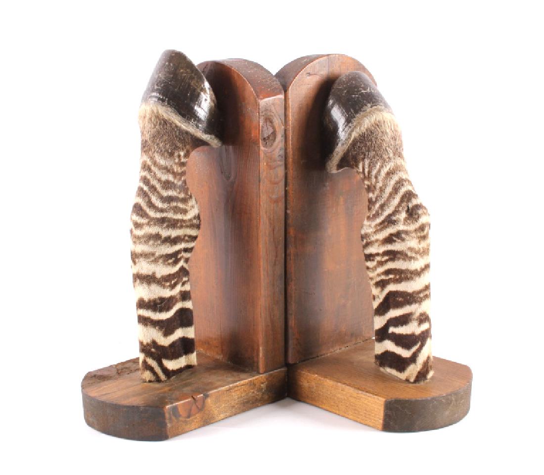 Taxidermy Zebra Leg Bookends: This is a pair of taxidermy zebra leg bookends. Each of the bookends is made from solid wood with the zebra leg at the center showing a wonderful striped fur. The zebra bookends are in good condition.