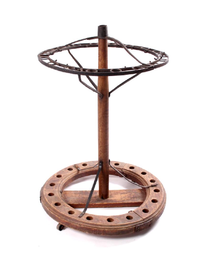 Antique Wooden Wrought Iron Fly Rod Holder: This is an antique wooden fly rod holder. The piece features a wooden base and upright with a wrought iron ring on the upper portion. The fly rod holder is in good condition. It measures 23" in diamet