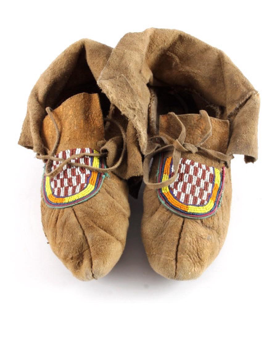 Northern Plains Moose Hide Beaded Moccasins: This is a pair of Northern Plains Native American Indian beaded moccasins from the early 1900's. The moccasins are made from tanned moose hide with fantastic beadwork done in Chalk White, Yellow, Pump