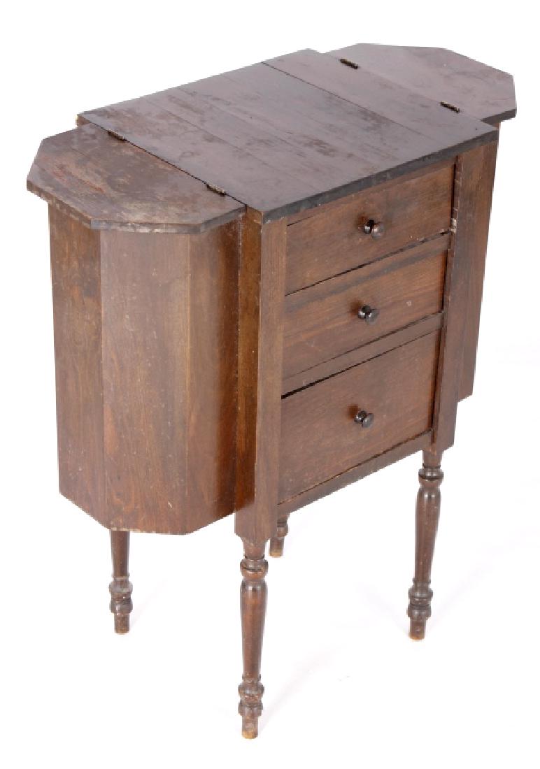 Early Walnut Sewing Periodical End Table 19th C.: You are bidding on a Early Walnut Sewing Sofa Periodical End Table. The table features a turned legs, lidded side cubbies, three drawers, and solid design. The drawers features appealing wooden pulls.