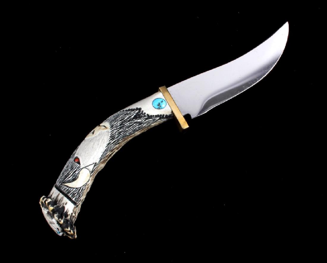 Custom Carved Elk Antler Knife: This is a custom made carved elk antler knife. The knife has a gently curved stainless steel blade and features a carved antler handle with a brass bolster and inlaid turquoise. The handle shows a car