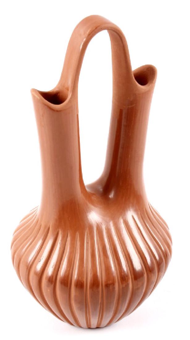 Signed Jemez Pueblo Traditional Red Wedding Vase: This lot holds a Jemez Pueblo Native American Indian traditional wedding vase. The wedding vase has vertical ribs decorating the lower portion, and a two tone, geometric bridge. The piece is signed on