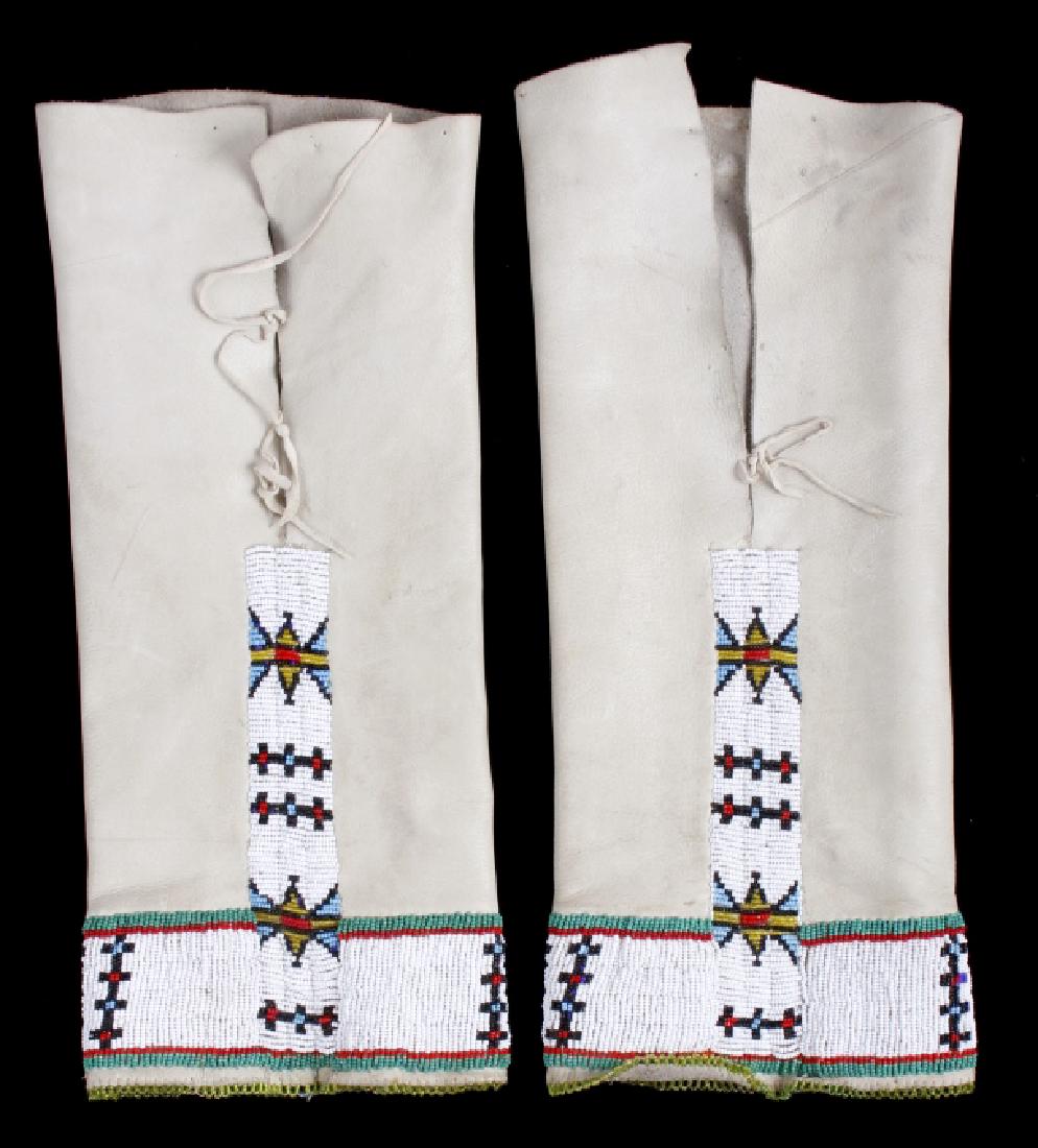 Sioux Tanned Hide Trade Seed Beaded Leggings: This lot holds a pair of Sioux Native American Indian leggings. The leggings are constructed of bright khaki, tanned hide - adorned with trade seed bead work, in a geometric motif. The bead work consi