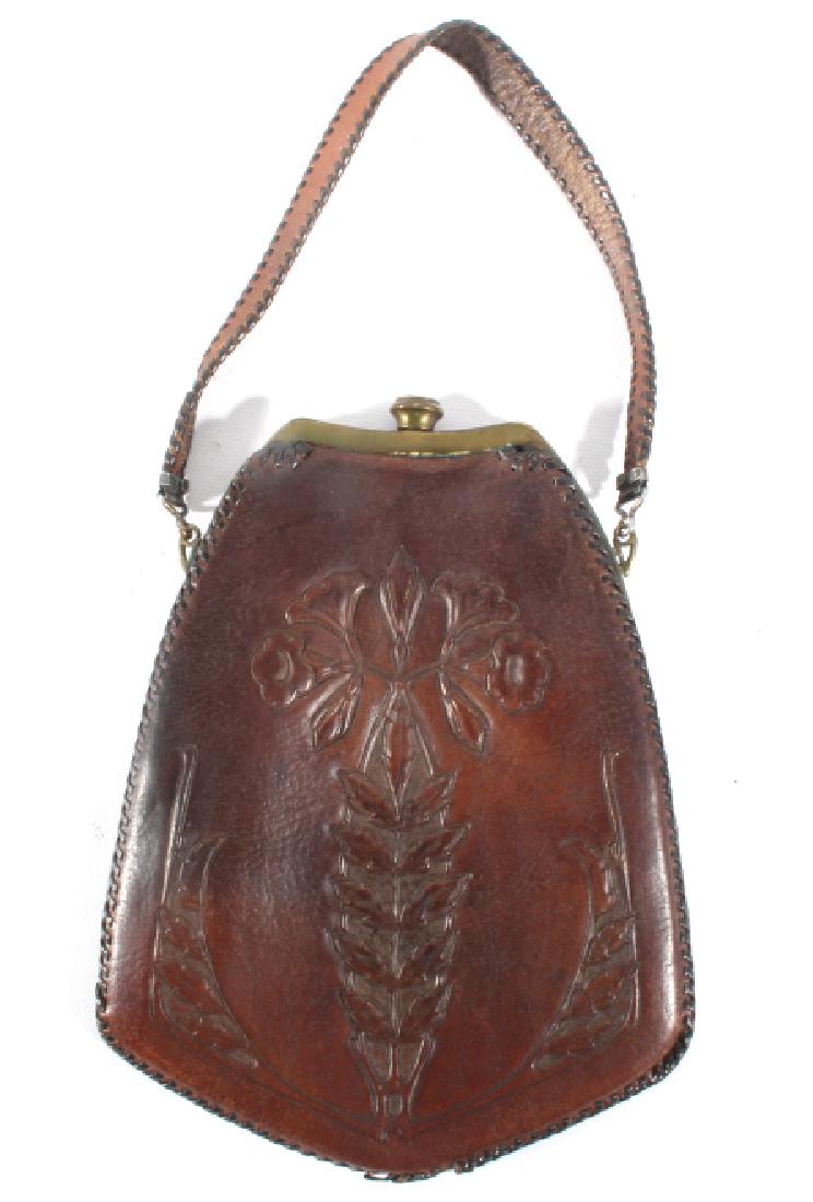 World War II Tooled Leather & Brass Hand Bag 1941: This lot features a Early Tooled Leather & Brass Hand Bag. The bag features a tooled front design, brass catch, small leather strap, stitched edges, and original receipt dated 1941. This bag shows goo