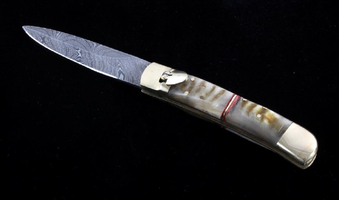 German Damascus Lever Lock Switchblade Knife: This is a German made lever lock switchblade knife. The knife features a Damascus blade with brass bolsters and genuine ram's horn handle. The lever on the left side of the handle releases the blade a