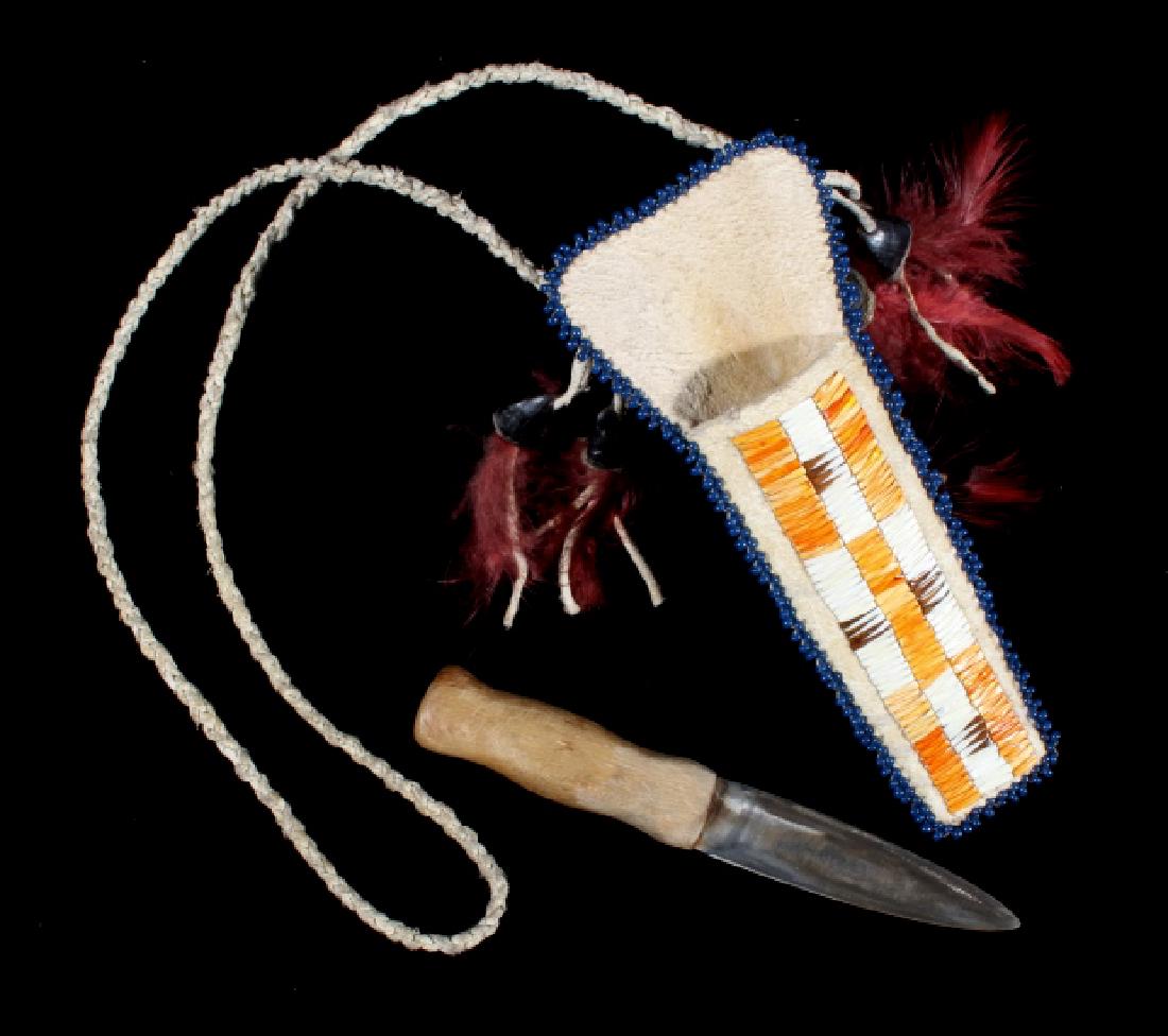 Crow Dag Knife & Quill Parfleche Necklace Scabbard: Available in this lot is a Crow Native American Indian dag knife and scabbard. The dag knife features a very sharp double edged 3" blade, and a ergonomical wooden handle. The knife is housed in a Parf